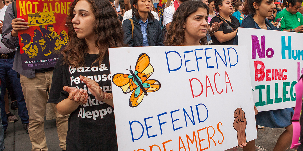 Photo of rally with people holding signs supporting DACA program and U.S. immigrants